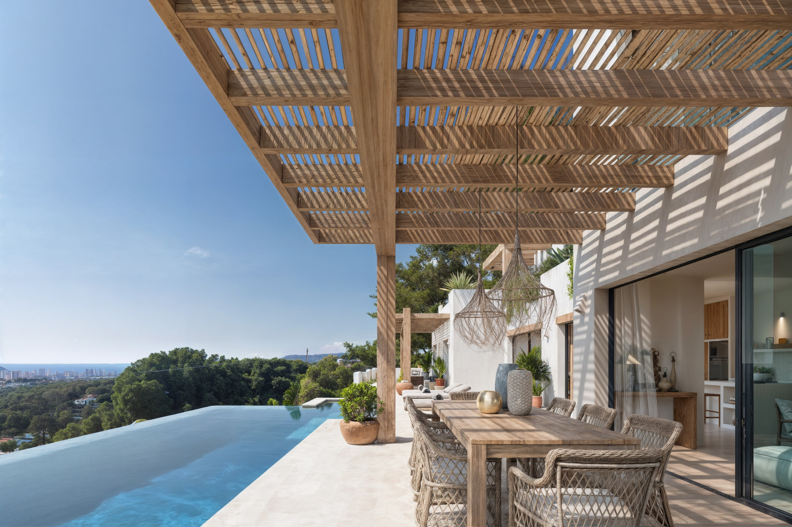 Außenbereich mit Holzpergola, Essplatz und Infinity-Pool mit Panoramablick auf das Mittelmeer und die Küstenlandschaft von Benissa.