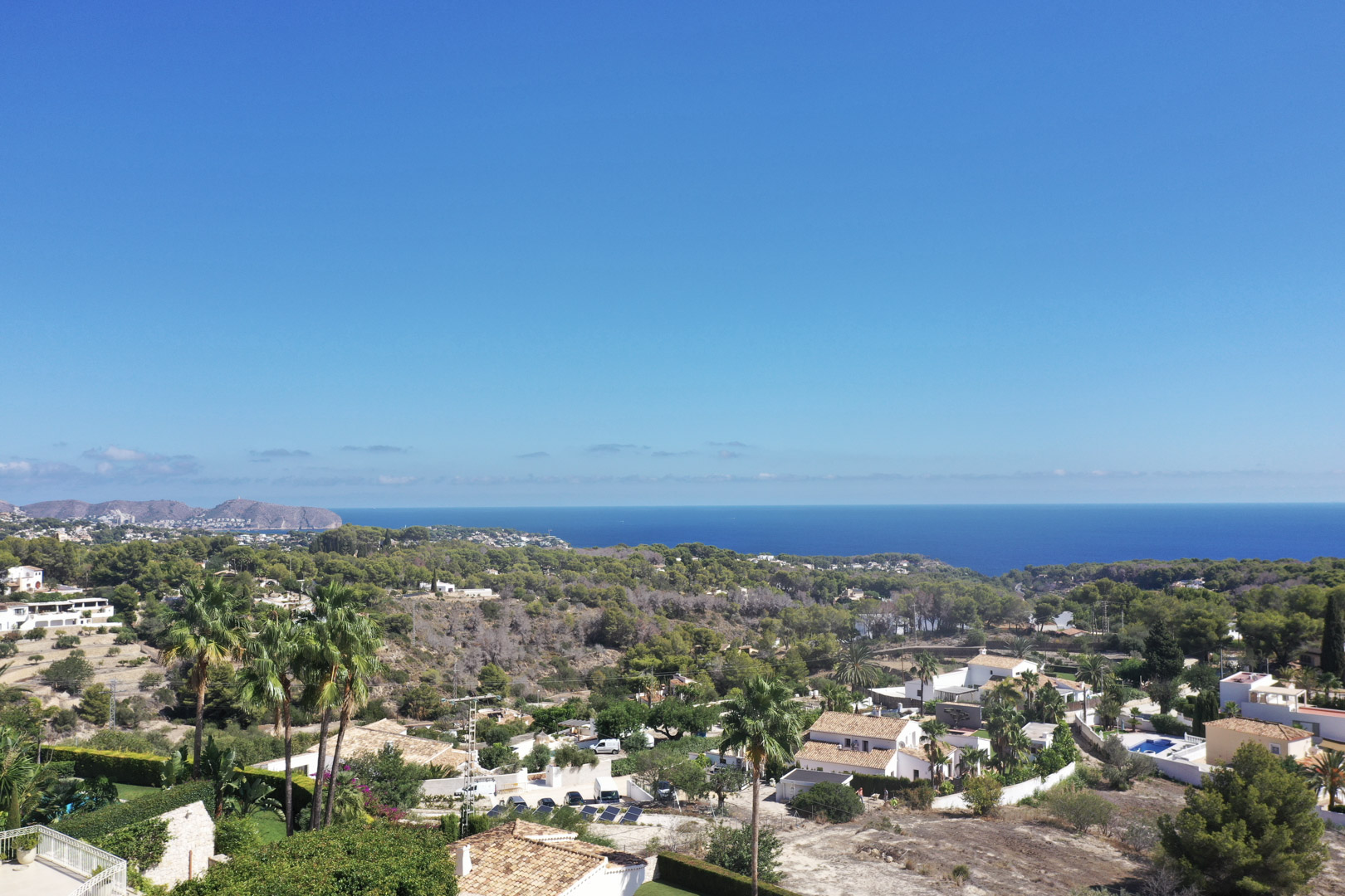 Erhöhter Panoramablick von Racó de Galeno auf das Mittelmeer, mit Küstenvegetation und Wohnvillen in Benissa unter einem klaren blauen Himmel.
