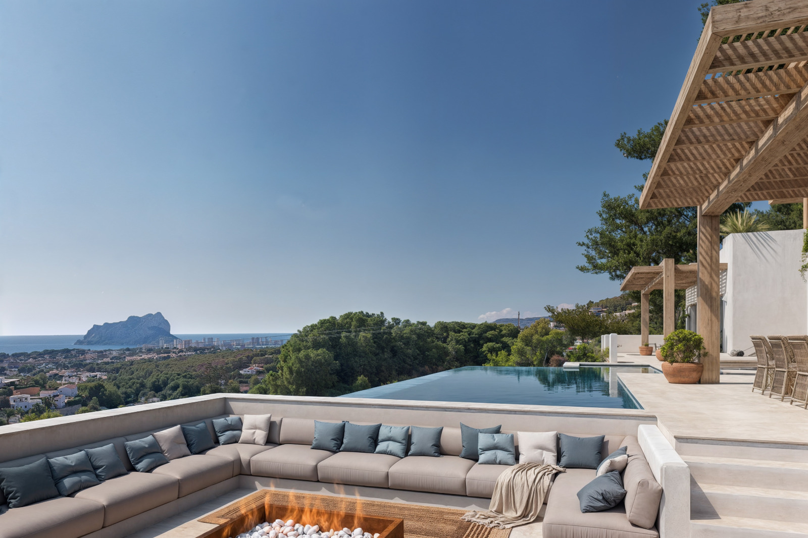 Versenkter Loungebereich mit zentraler Feuerstelle, angrenzendem Infinity-Pool und Panoramablick auf das Mittelmeer und den markanten Peñón de Ifach.