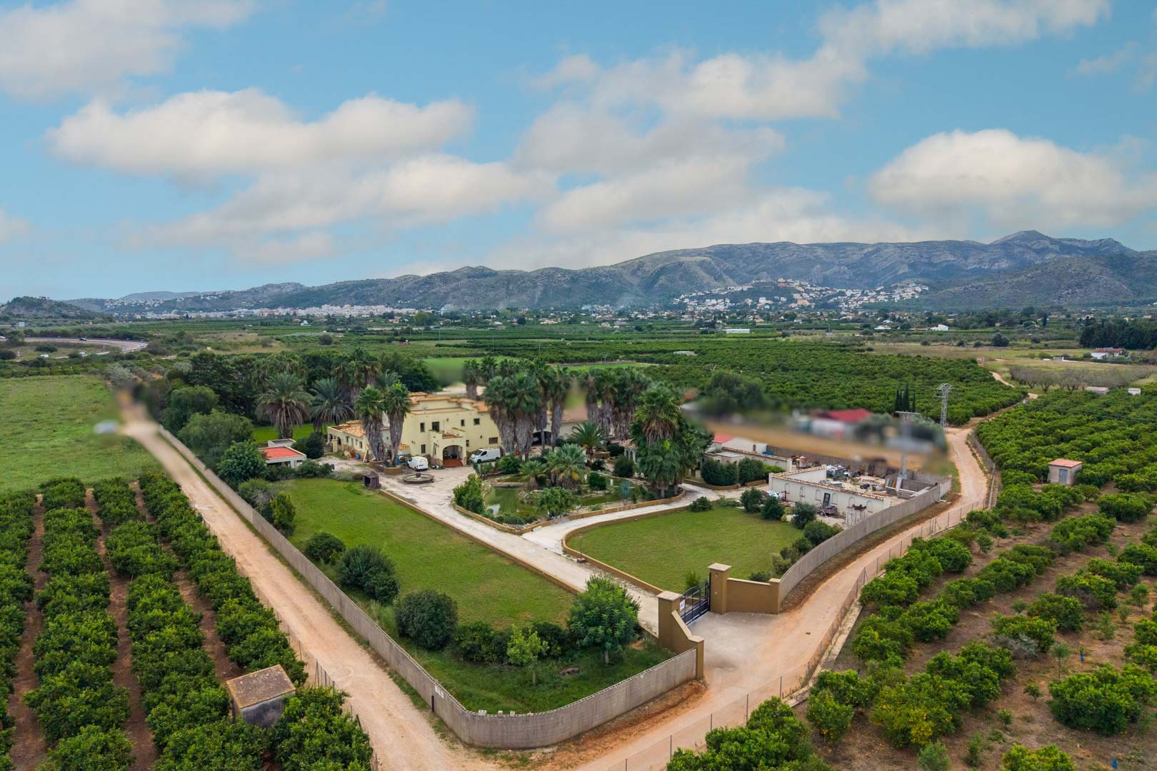 Luftaufnahme des 10.000 m² großen Anwesens mit dem Haupthaus, dem zentralen Teich und den Gärten, umgeben von Zitrusplantagen und einer Bergkulisse.