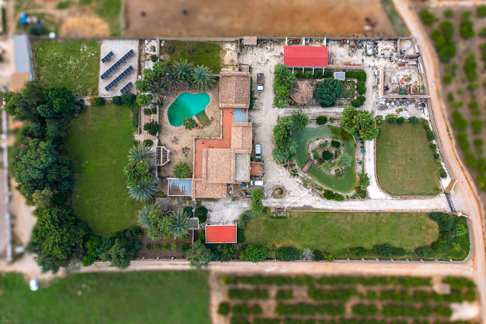 Luftaufnahme des Anwesens mit Haupthaus, Pool, japanischem Teich, weitläufigen Rasenflächen und der Photovoltaikanlage auf dem 10.000 m2 großen Grundstück.