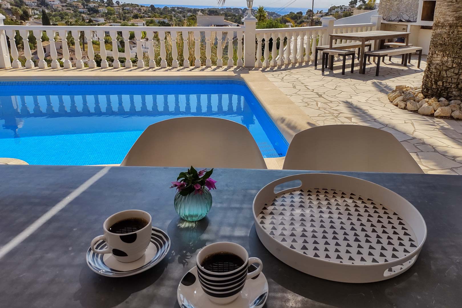 Hauptterrasse mit privatem Pool und Meerblick. Verfügt über einen Essbereich im Freien mit Holztisch und Bänken auf Natursteinpflaster und weißer Balustrade.