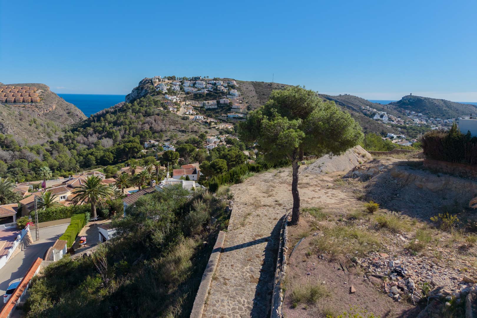 Erhöhter Panoramablick über das Tal von Moraira und das Mittelmeer, eingebettet in eine natürliche Landschaft mit Pinien.