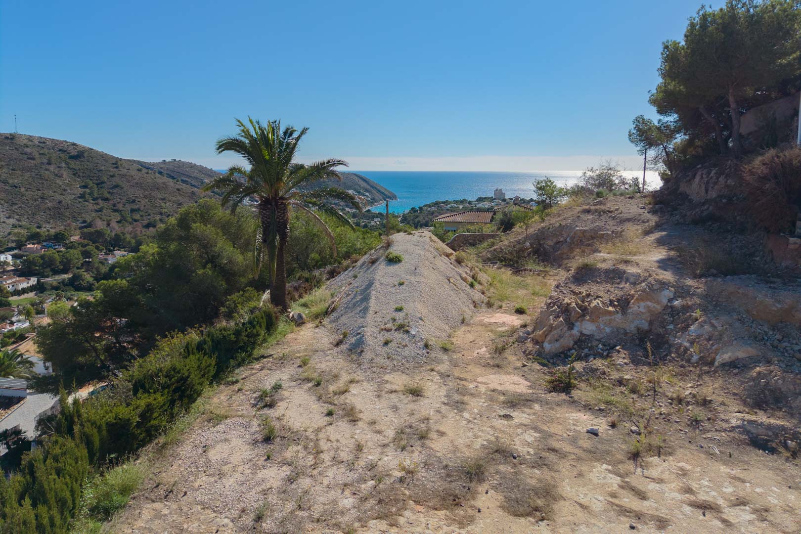 Panoramablick vom erhöhten Baugrundstück auf die Bucht von El Portet, der die natürliche mediterrane Umgebung und den weiten Meerblick in Moraira zeigt.