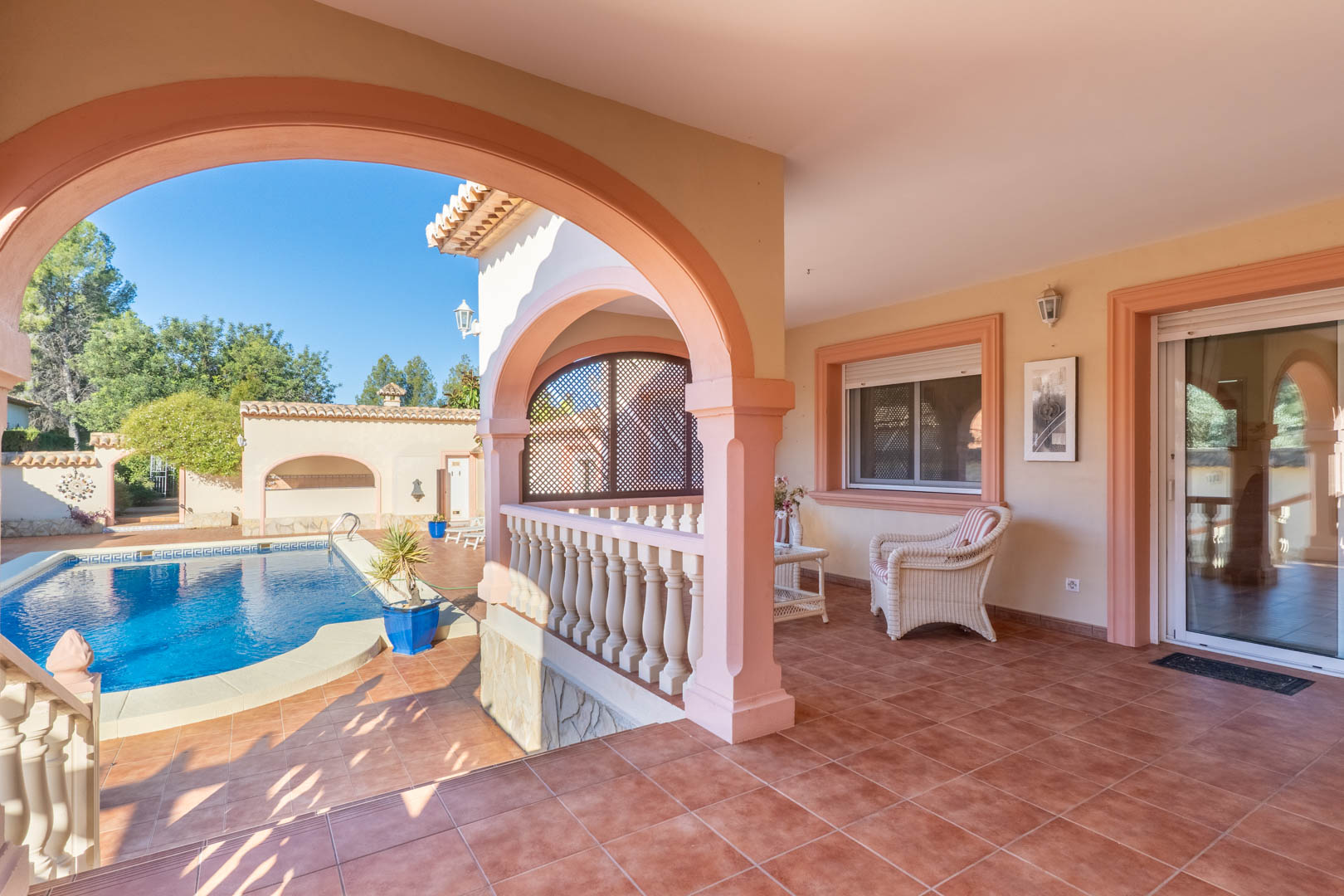 Großzügige überdachte Naya mit mediterranen Rundbögen, Terrakottaboden und Blick auf den privaten Pool sowie direktem Zugang zum Wohnbereich.