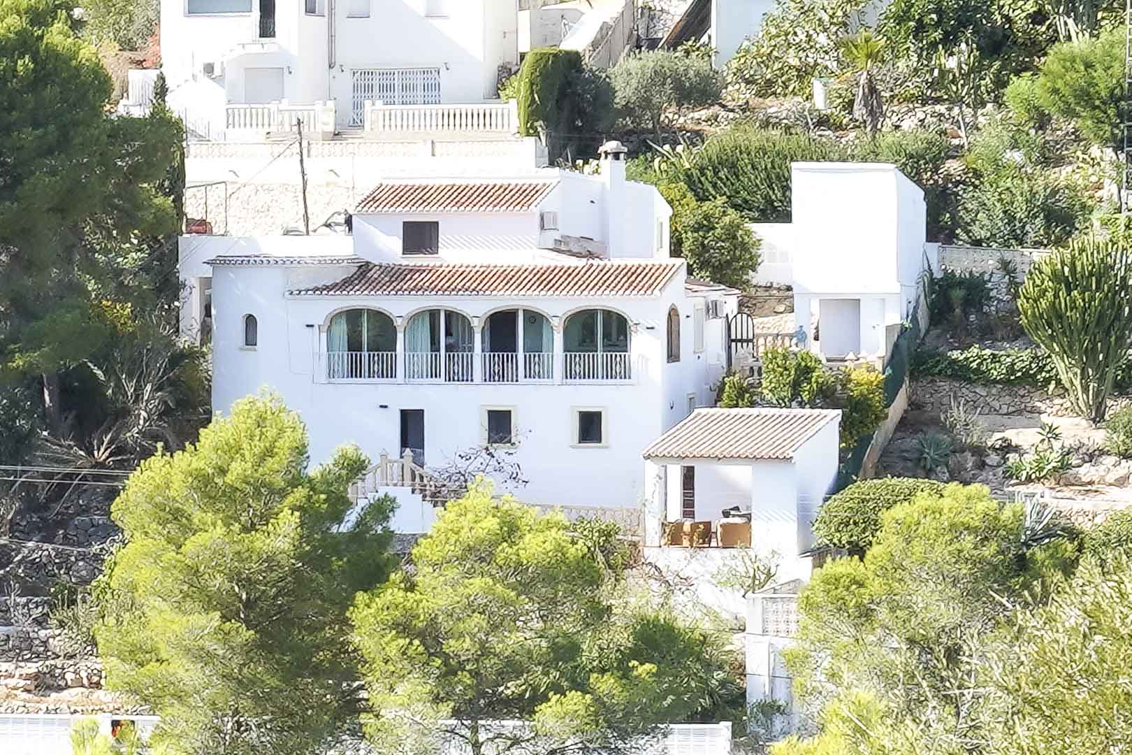 Außenansicht der weißen Villa mit traditionellen Ziegeldächern und einer Rundbogennaya, eingebettet in eine bewaldete Hanglage in Pinomar.