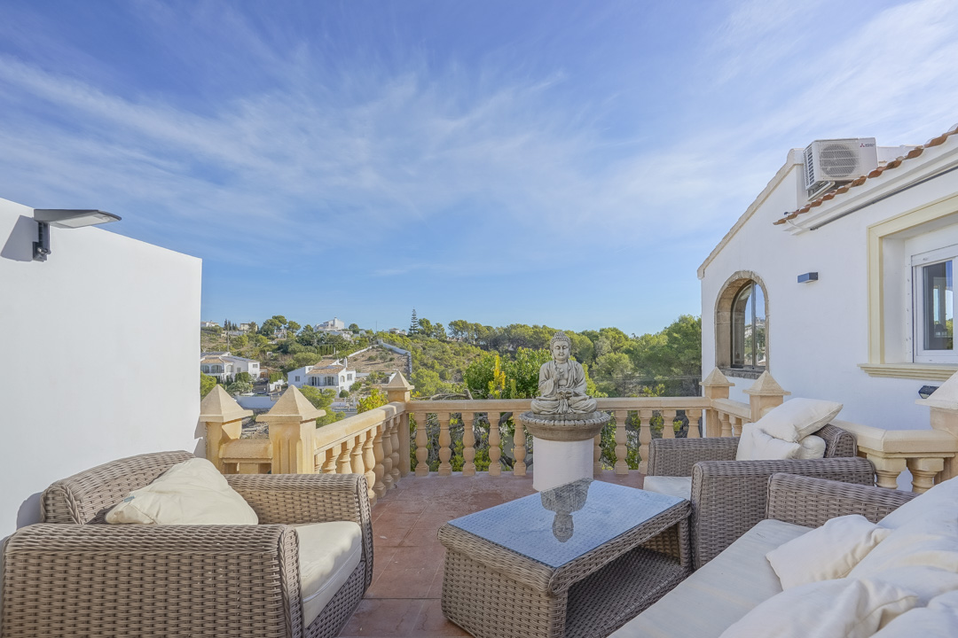 Hochgelegene Terrasse mit Rattan-Sitzgruppe, traditioneller Steinbalustrade und weitem Blick auf die umliegende Hügellandschaft und Pinienwälder.
