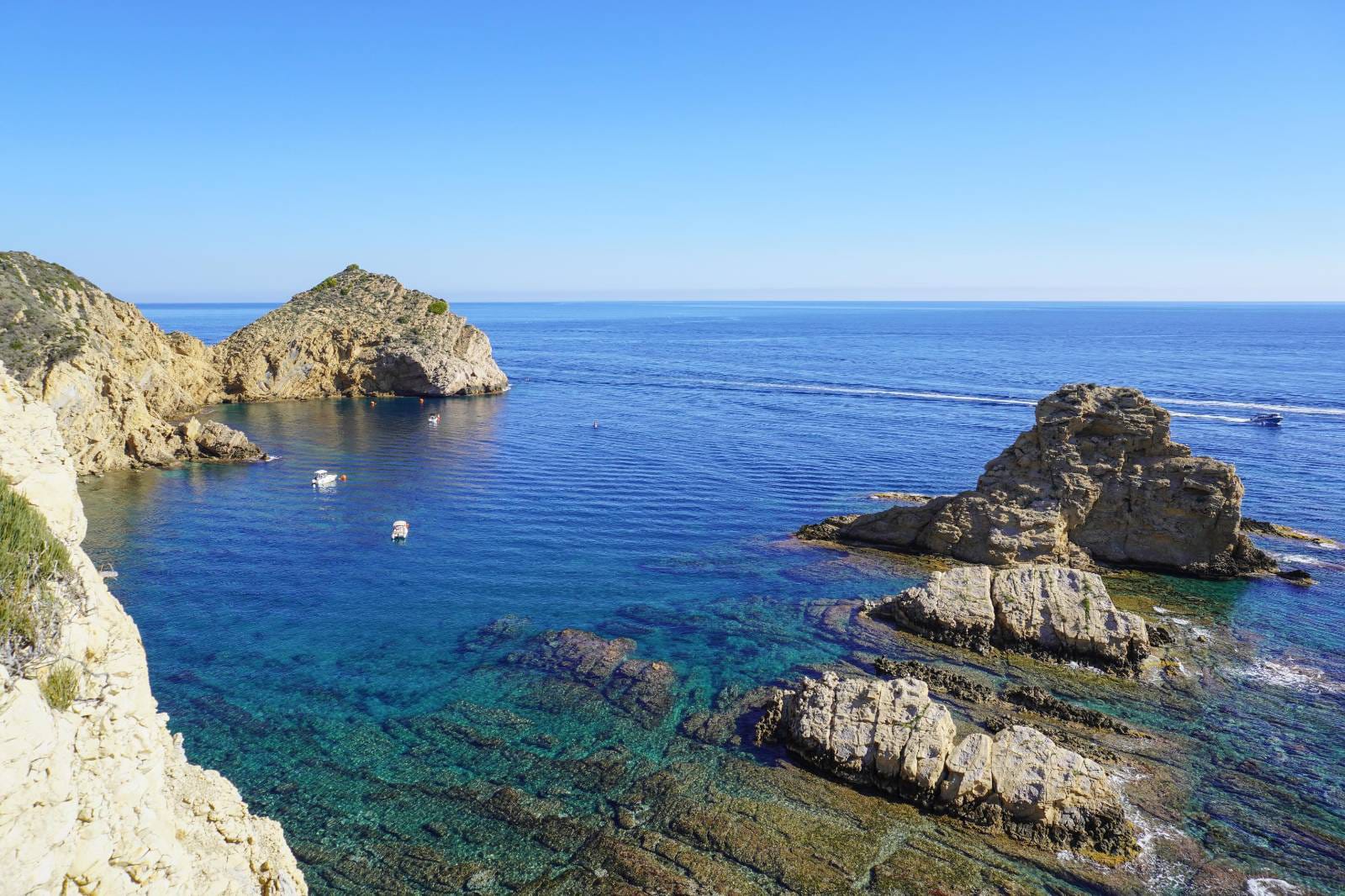 Panoramablick auf eine Bucht mit türkisblauem Wasser und Felsklippen in Jávea, die die küstennahe Umgebung der Villa zeigt.