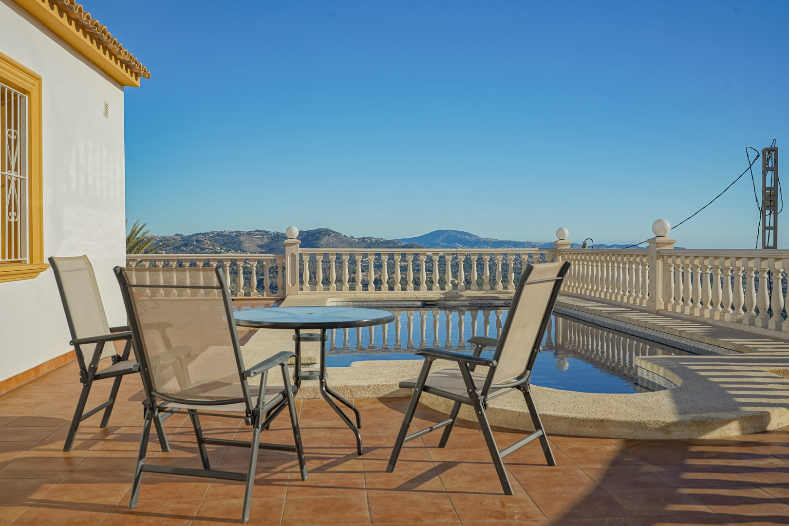 Außen-Terrasse mit Terrakotta-Fliesen, Sitzgruppe und privatem Pool, umgeben von einer klassischen Balustrade mit weitem Panoramablick auf die Berglandschaft.