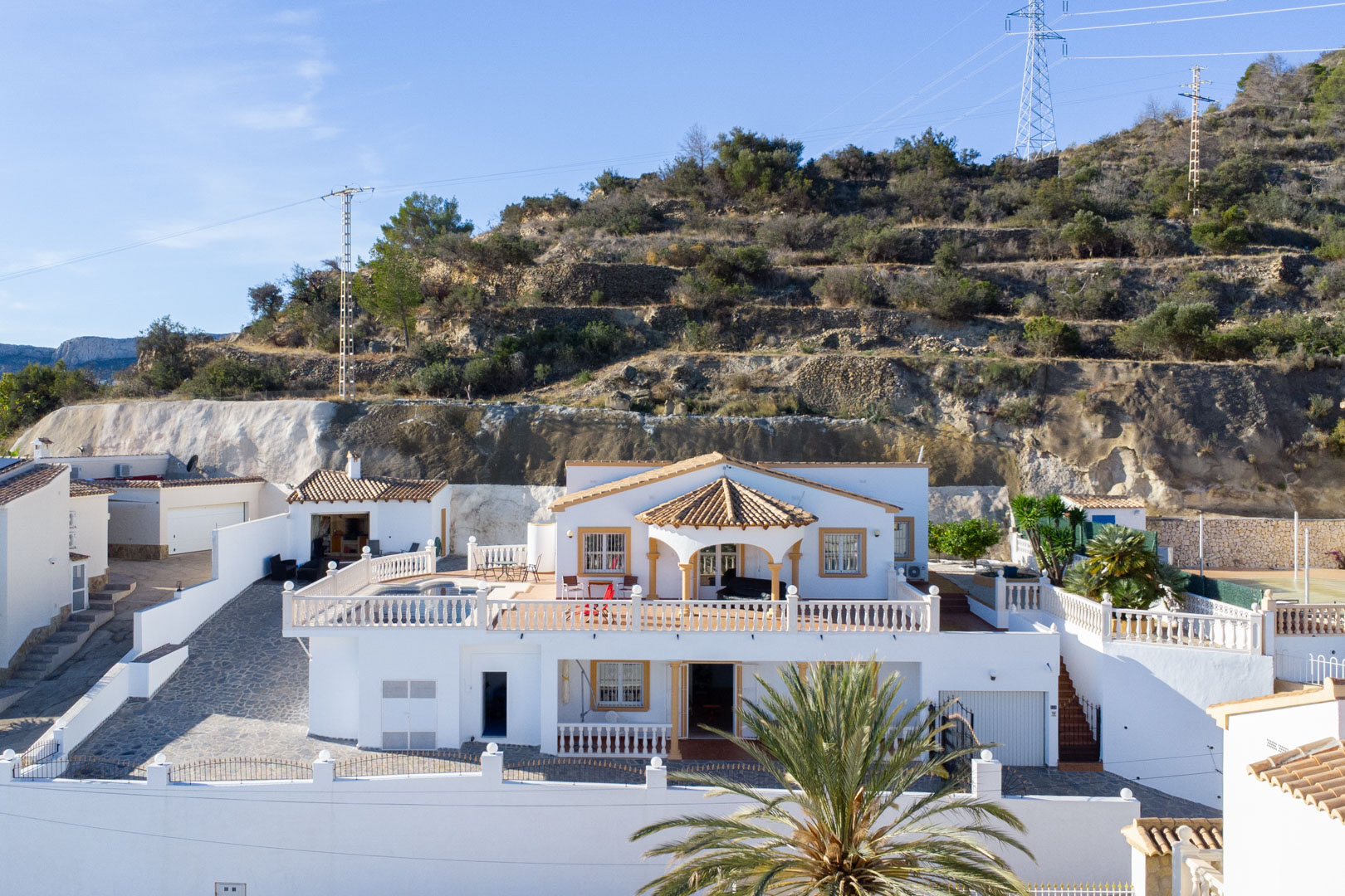 Außenansicht der zweistöckigen weißen Villa mit weitläufigen Terrassen, Balustraden, privatem Pool und Sommerküche am Hang der Sierra de Oltà.