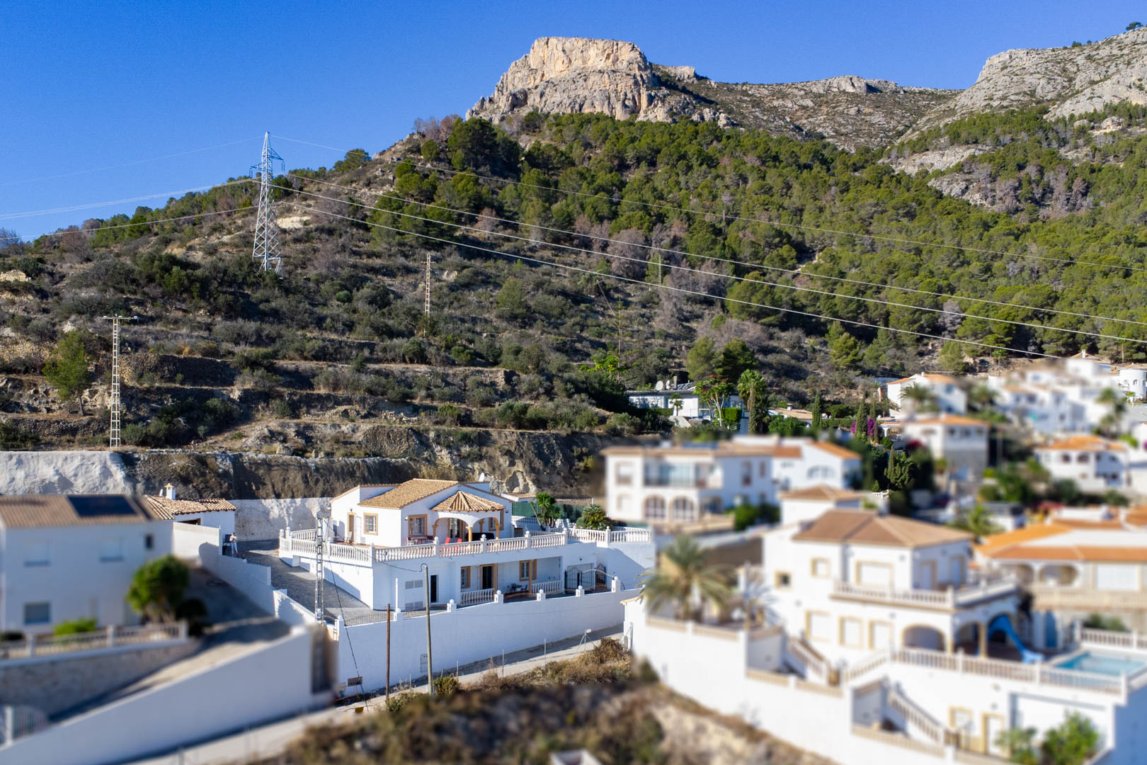 Erhöhte Ansicht der weißen Villa am Hang der Sierra de Oltà mit traditioneller Architektur, Ziegeldächern und weitläufigen Terrassen.