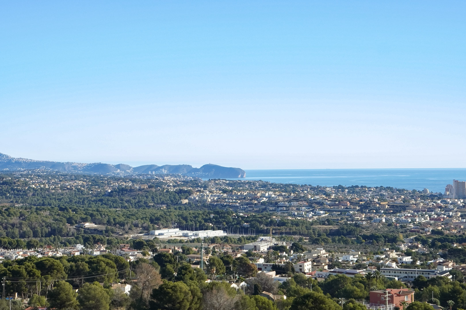 Erhöhter Panoramablick auf die Mittelmeerküste und das Cap d’Or, über die Wohngebiete und dichten Pinienwälder von Calpe.