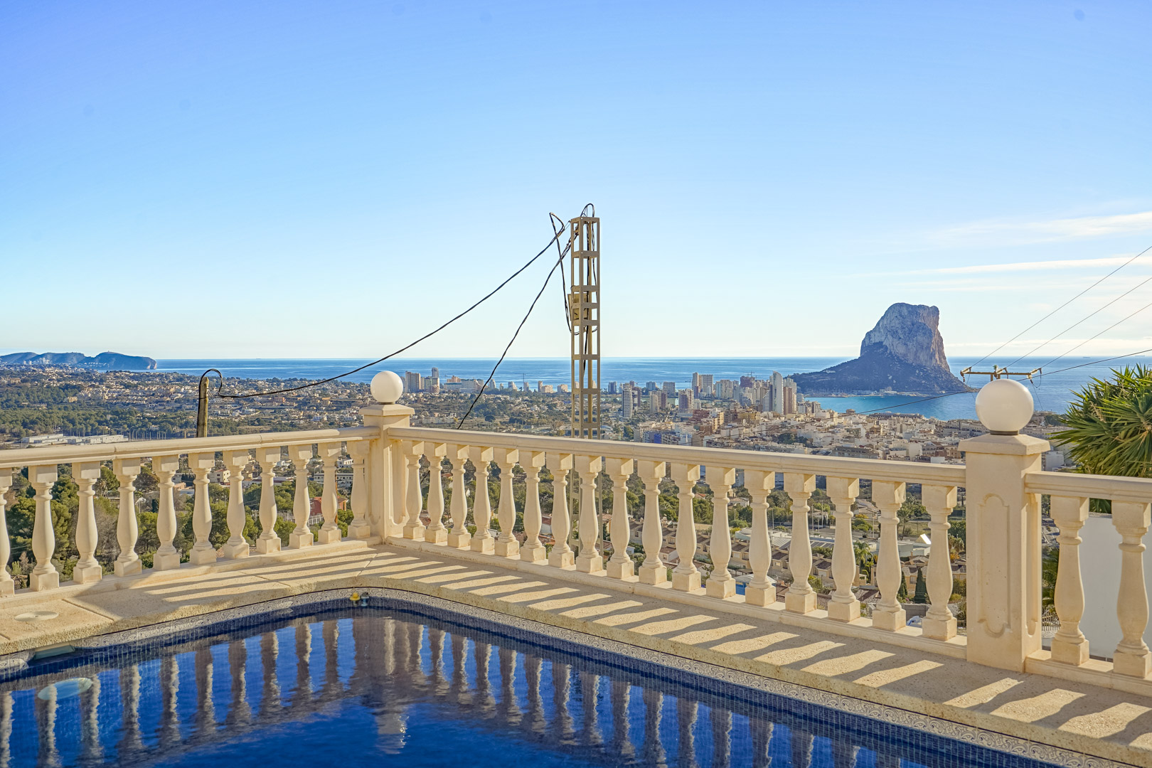 Poolterrasse mit klassischer Steinbalustrade und Panoramablick auf den Peñón de Ifach, die Skyline von Calpe und das Mittelmeer.