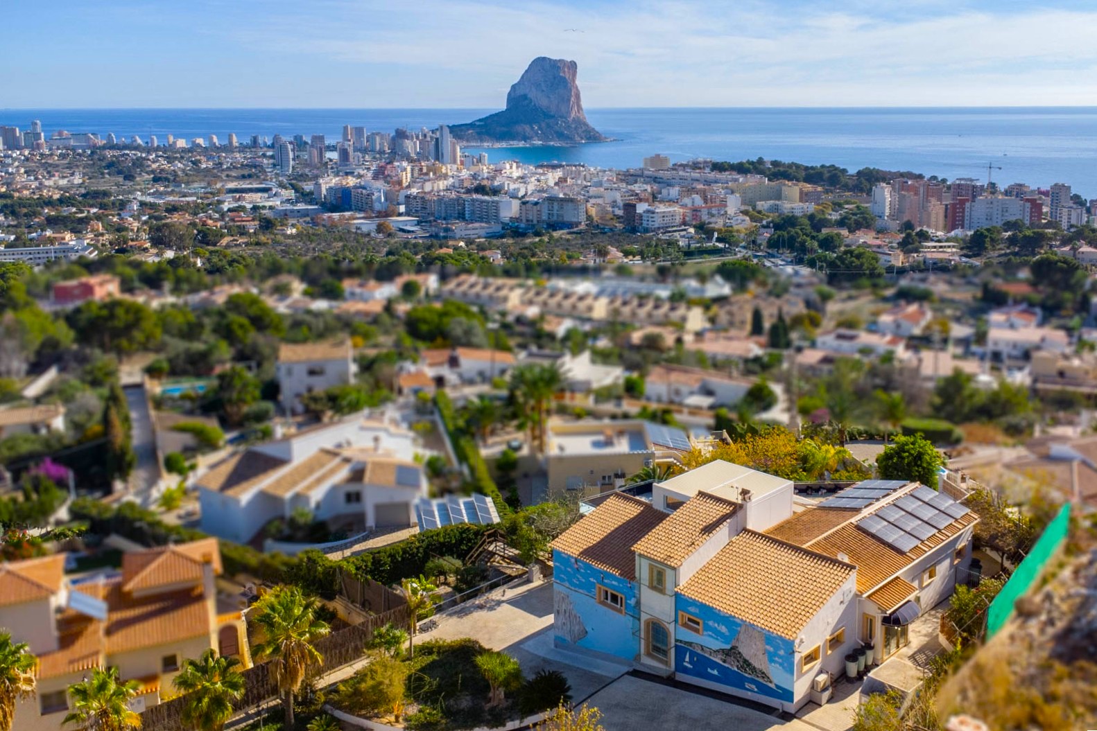 Erhöhte Ansicht der Villa mit Solarmodulen und Wandgemälde, die einen weiten Blick auf die Skyline von Calpe und den Peñón de Ifach bietet.