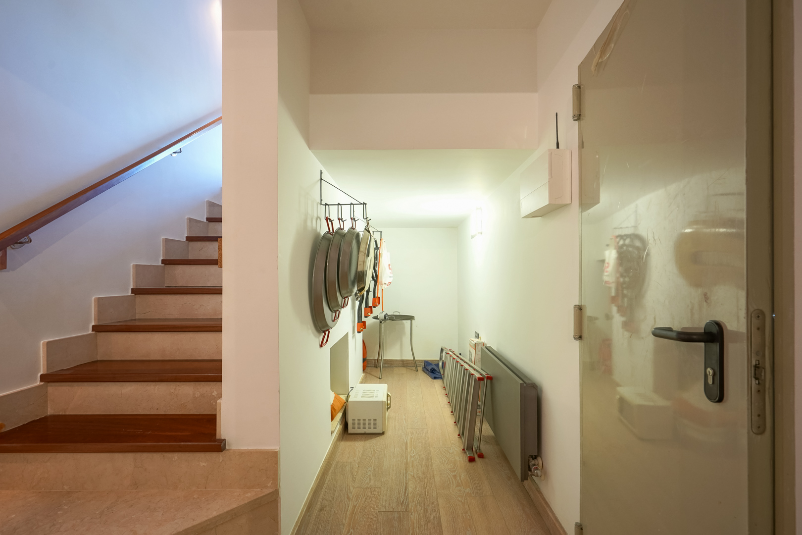 Funktionaler Flur mit Stauraum für Kochutensilien neben einer Treppe aus Stein und Edelholz mit modernem Handlauf.