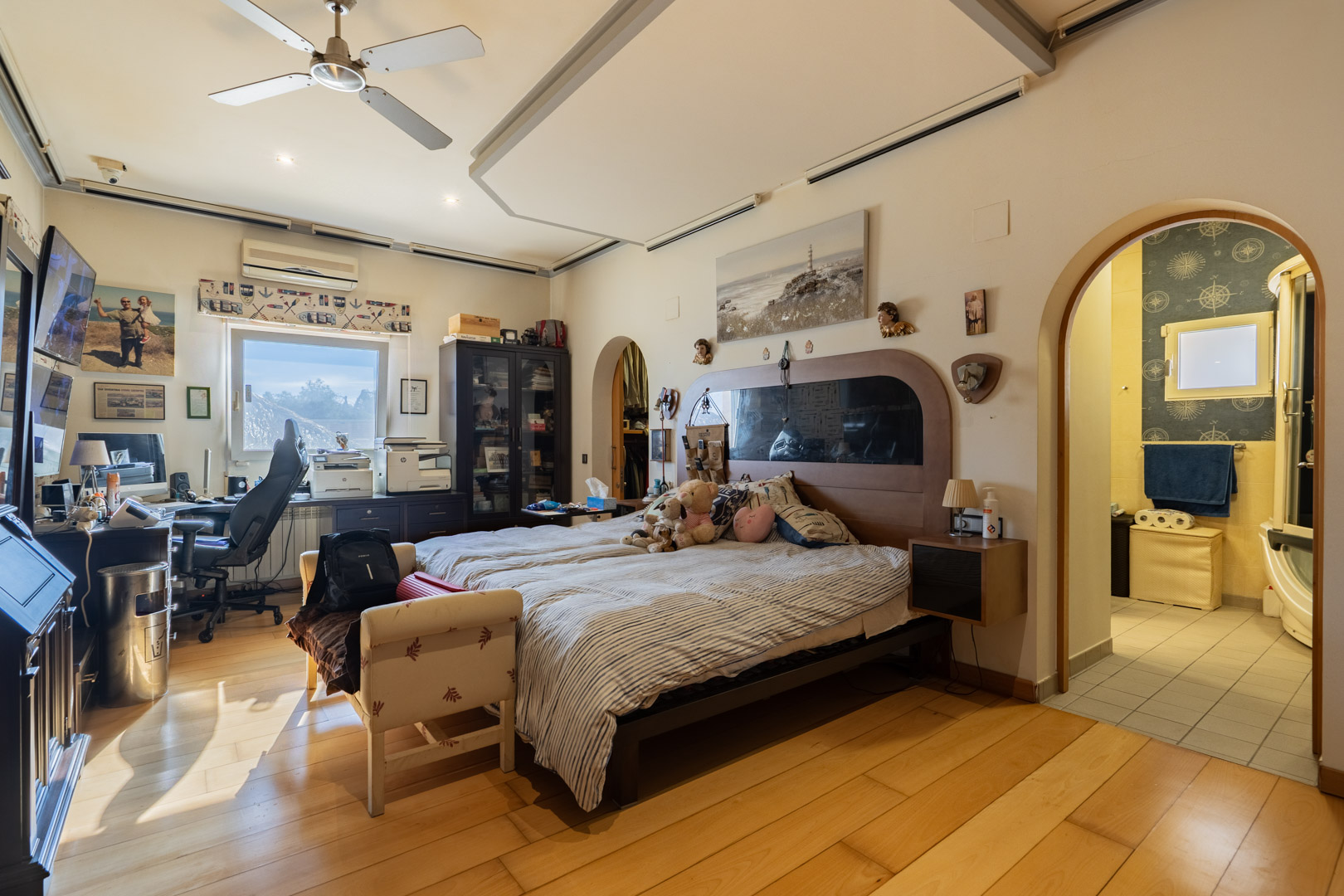 Hauptschlafzimmer mit edlen Holzböden, integriertem Arbeitsbereich und En-Suite-Badezimmer. Ausgestattet mit Deckenventilator und Klimaanlage.