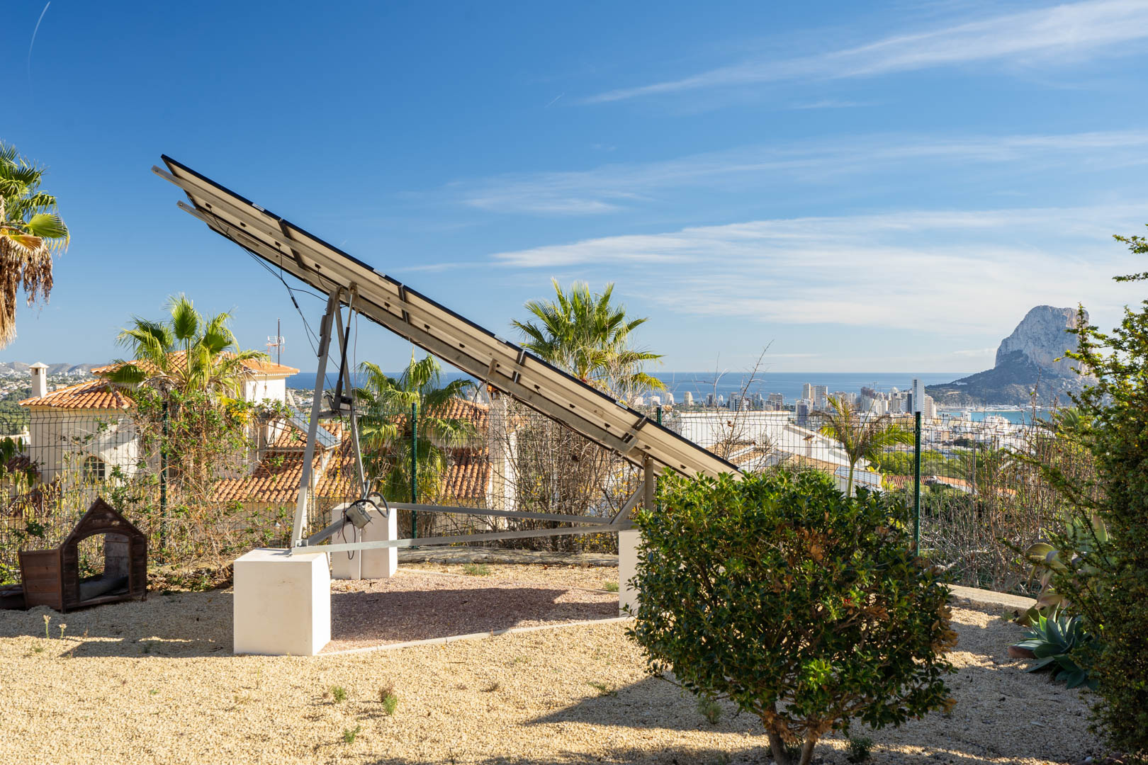 Motorisierte Solarnachführanlage auf einem Kiesgrundstück mit Panoramablick auf die Skyline von Calpe und den markanten Peñón de Ifach.
