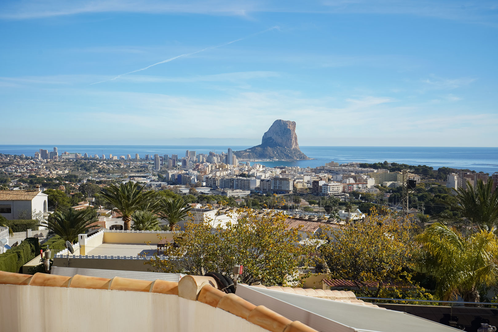 Panoramablick von der Terrasse auf den Peñón de Ifach, die Skyline von Calpe und das Mittelmeer, umgeben von mediterraner Vegetation und Wohngebieten.