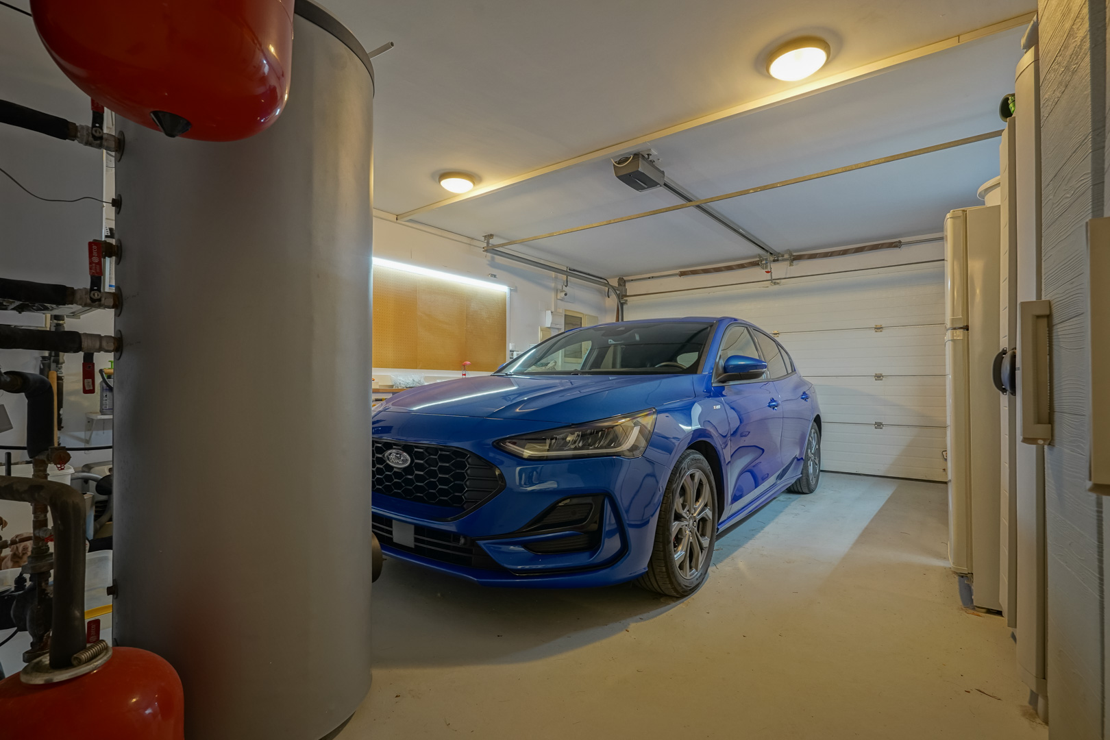 Private Garage mit automatischem Sektionaltor, LED-beleuchtetem Werkstattbereich und technischen Anlagen zur Warmwasserbereitung.