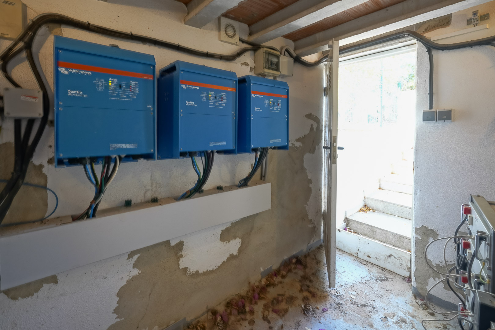 Technikraum mit drei Victron Energy Quattro Wechselrichtern der Photovoltaikanlage, gelegen in einem Raum mit direktem Außenzugang.