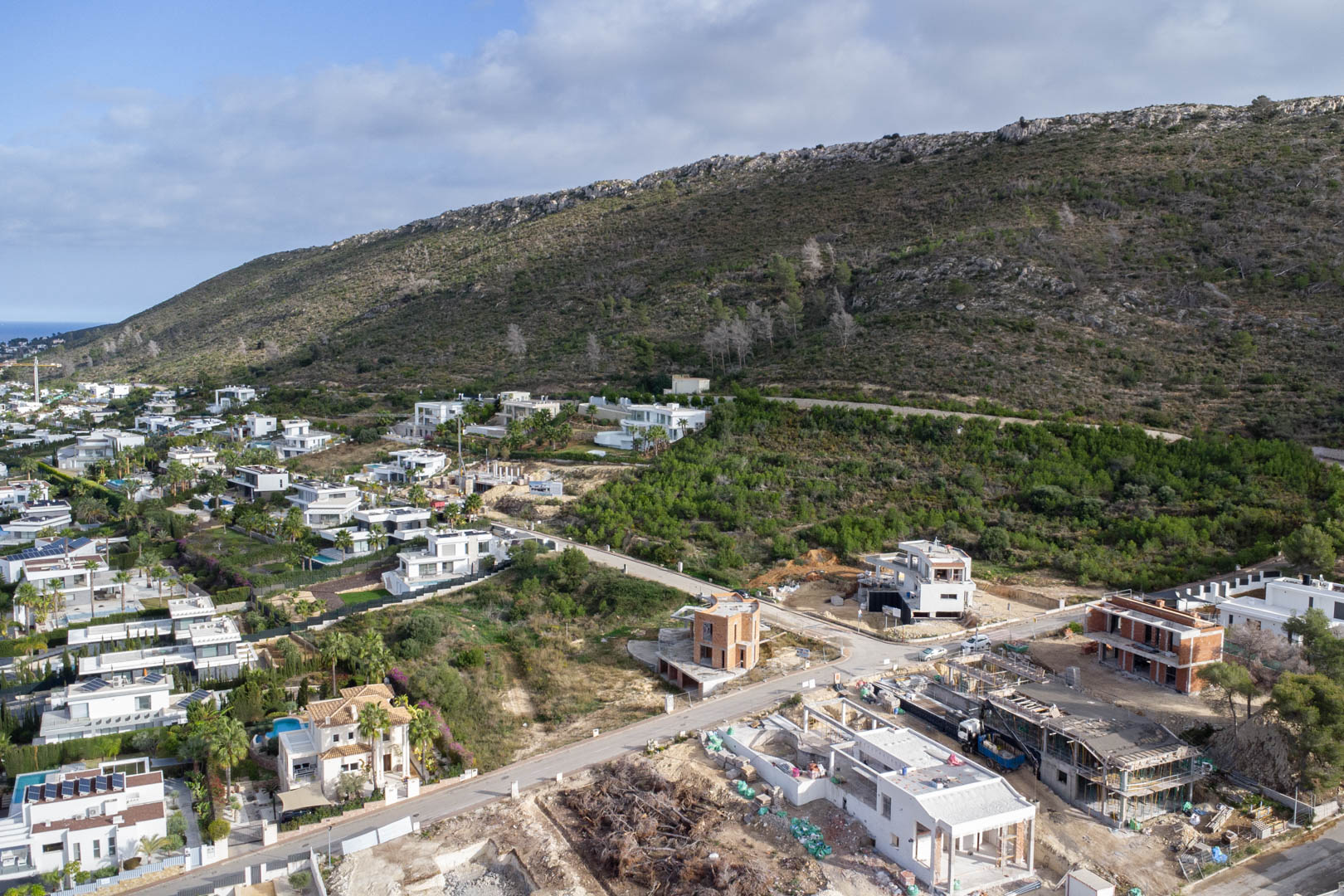 Luftaufnahme des Wohngebiets Monte Olímpico mit erschlossenen Grundstücken, asphaltierten Straßen, Straßenbeleuchtung und modernen Villen am Hang.