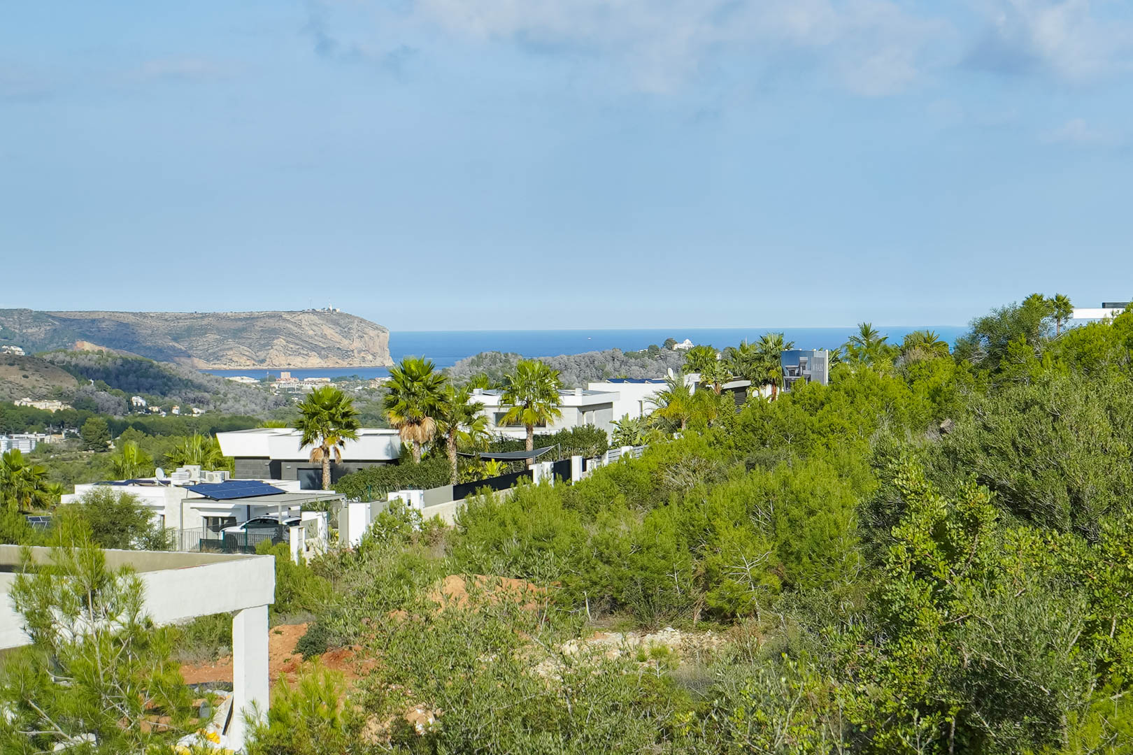 Panoramablick auf das Mittelmeer und das Cabo de San Antonio vom Grundstück aus, umgeben von modernen Villen und mediterraner Vegetation.
