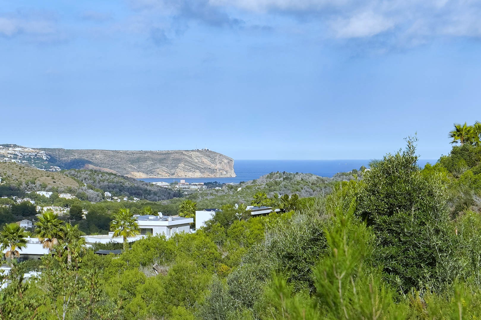 Panoramablick vom Grundstück auf das Mittelmeer und das Cabo de San Antonio, eingebettet in mediterrane Vegetation und moderne Villen.