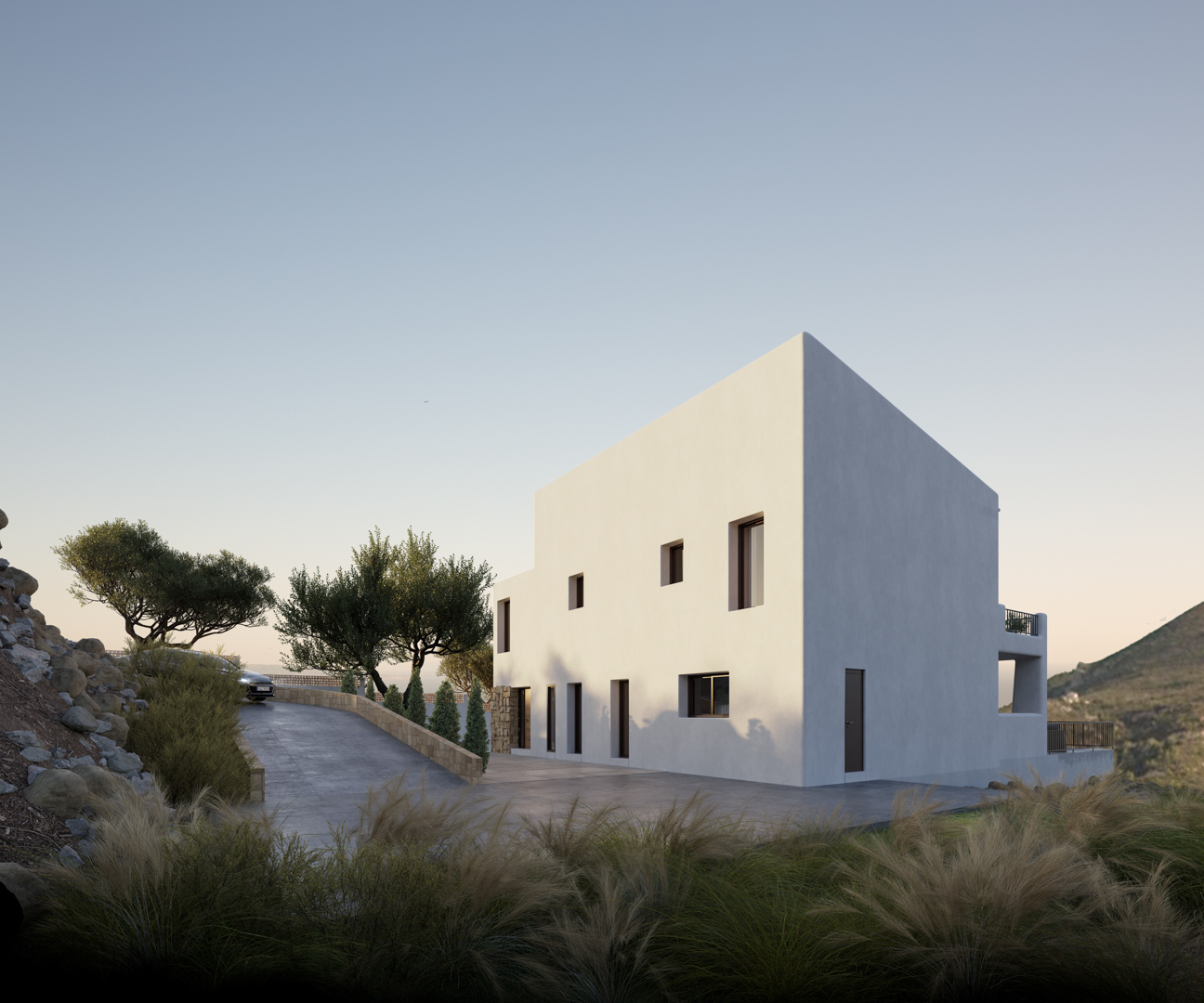 Außenansicht der Villa im ibizenkischen Stil mit minimalistischer weißer Fassade, gepflasterter Auffahrt und in die Landschaft von Alcalalí integrierten Natursteinmauern.
