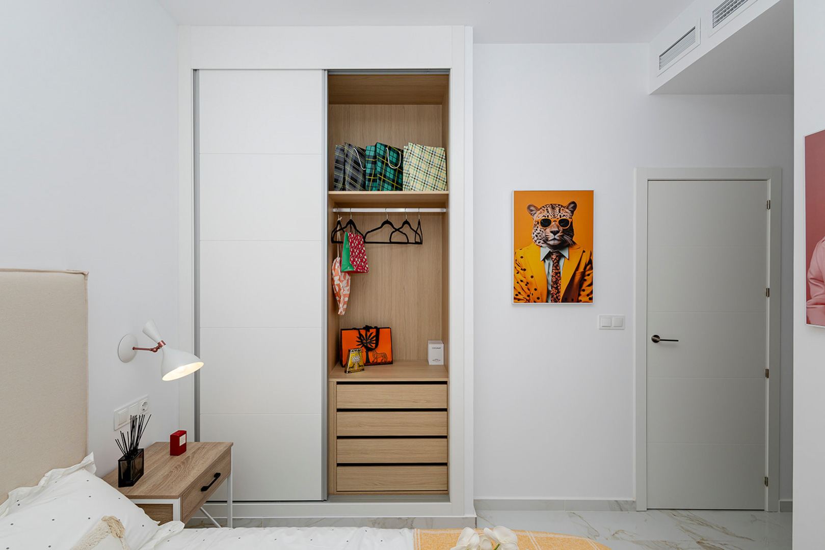 Schlafzimmer mit Einbauschrank, weißen Schiebetüren und Holzinnenausbau. Ausgestattet mit Bodenfliesen in Marmoroptik und integrierter Kanalklimaanlage.