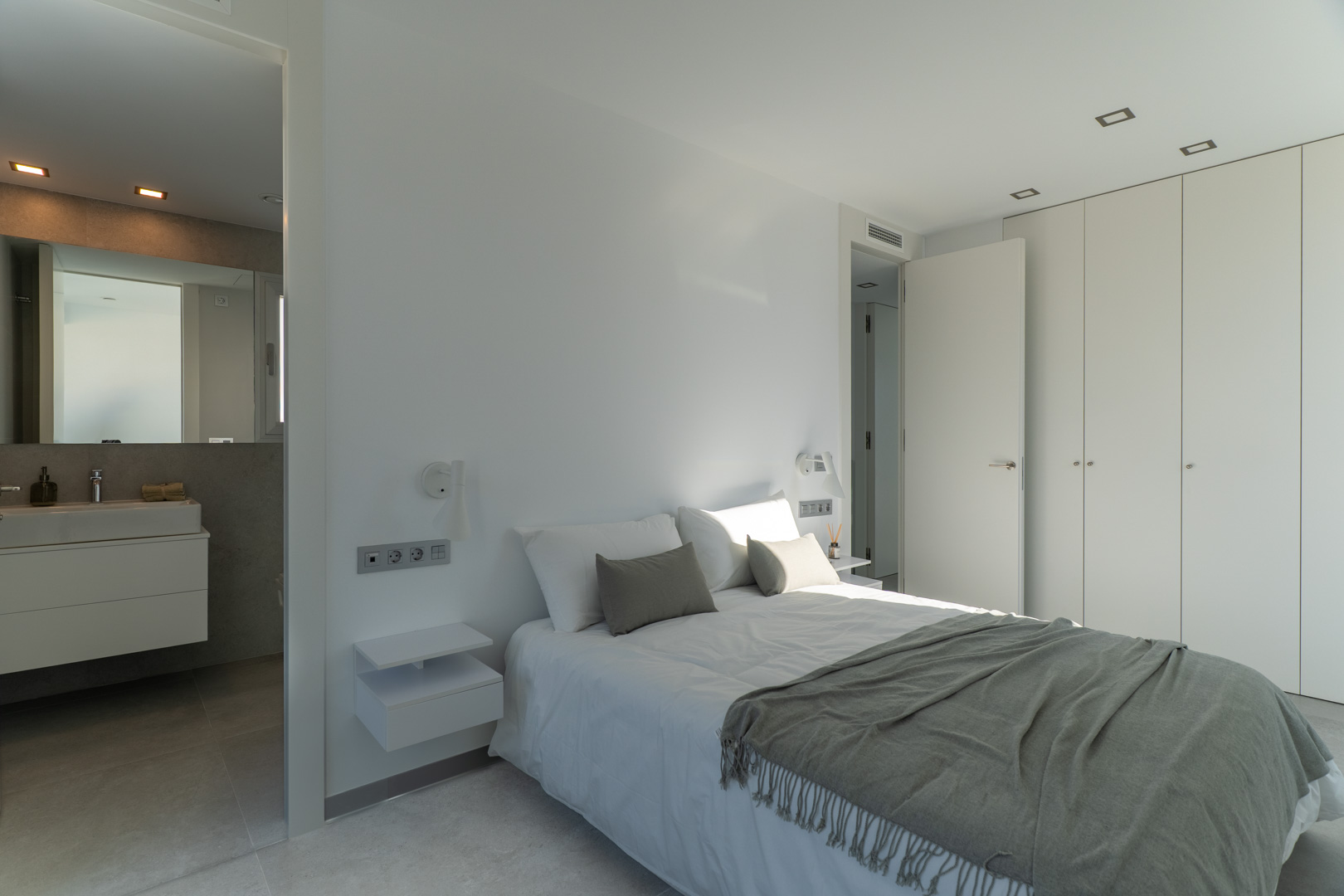 Hauptschlafzimmer mit En-Suite-Bad, raumhohen Einbauschränken und minimalistischem Design mit integrierter Deckenbeleuchtung.
