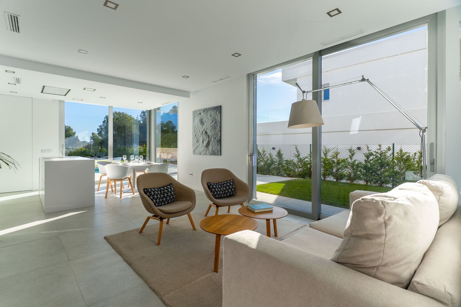 Offener Wohnbereich mit bodentiefen Glasfronten, modernem Design in Naturtönen und direktem Zugang zum gepflegten Gartenanteil.