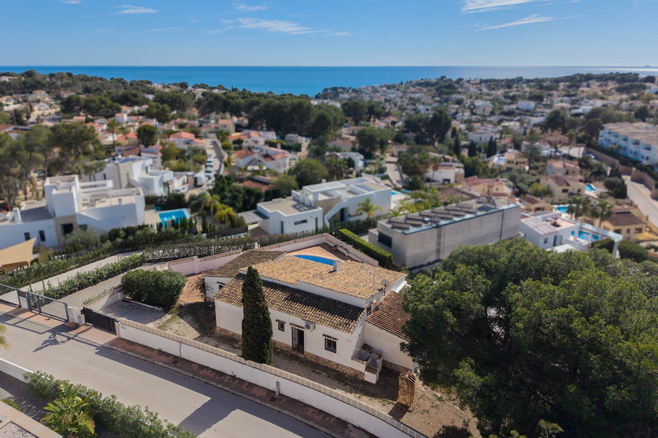 Luftaufnahme der Villa in Benissa Costa, die die mediterrane Architektur mit Ziegeldächern, das private Grundstück mit Zypressen und den Meerblick zeigt.