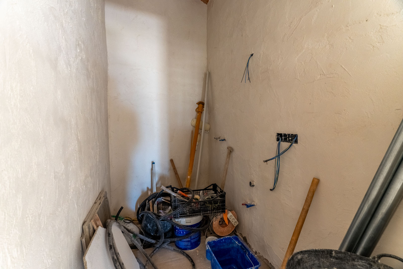 Innenraum in der Renovierungsphase mit verputzten Wänden, sichtbaren Elektroinstallationen und Baumaterialien für den weiteren Ausbau.