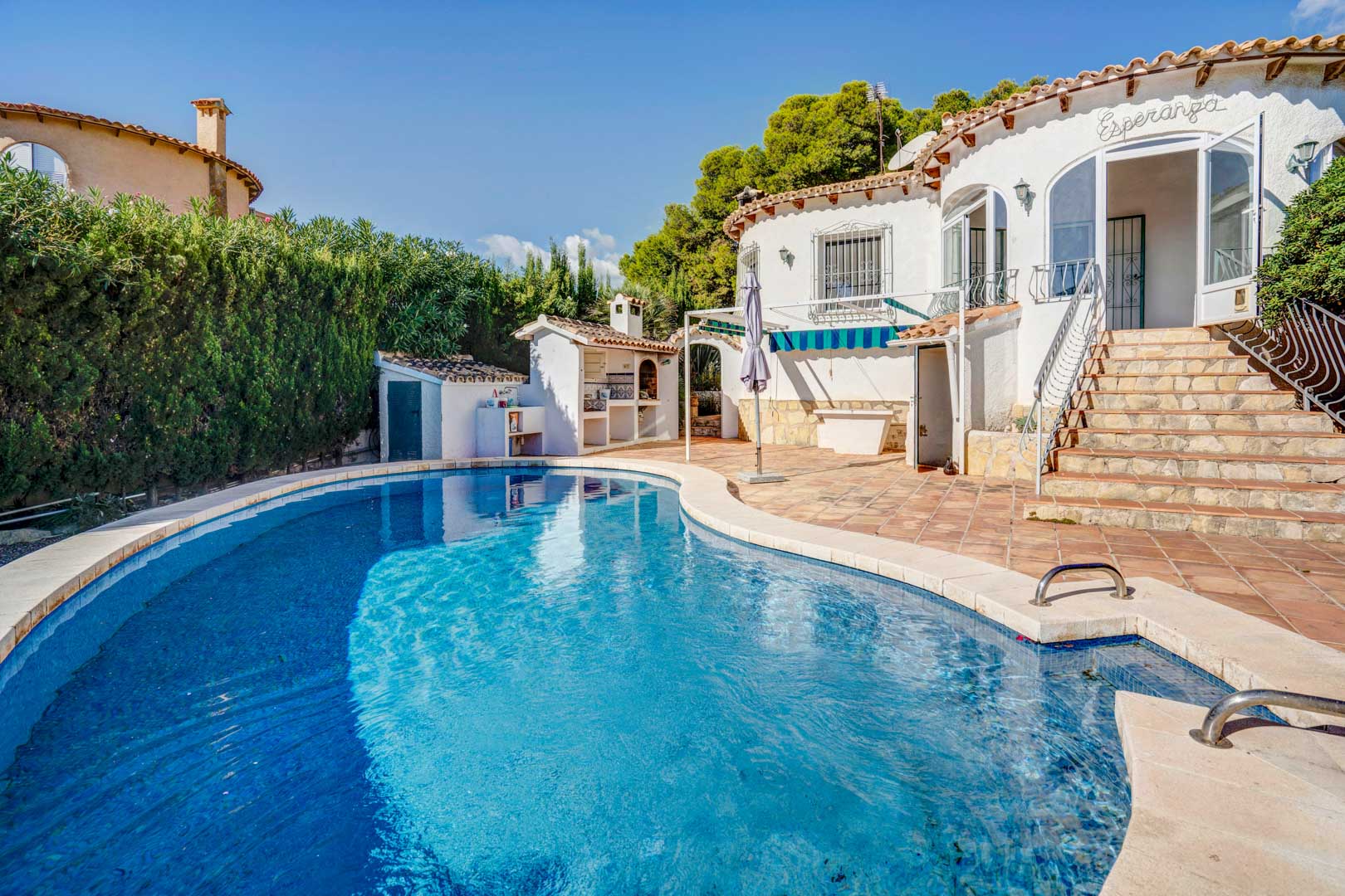 Privater Poolbereich mit umlaufender Terrakotta-Terrasse, gemauertem Außen-Grillplatz und Steintreppe zum verglasten Eingangsbereich des Hauses.