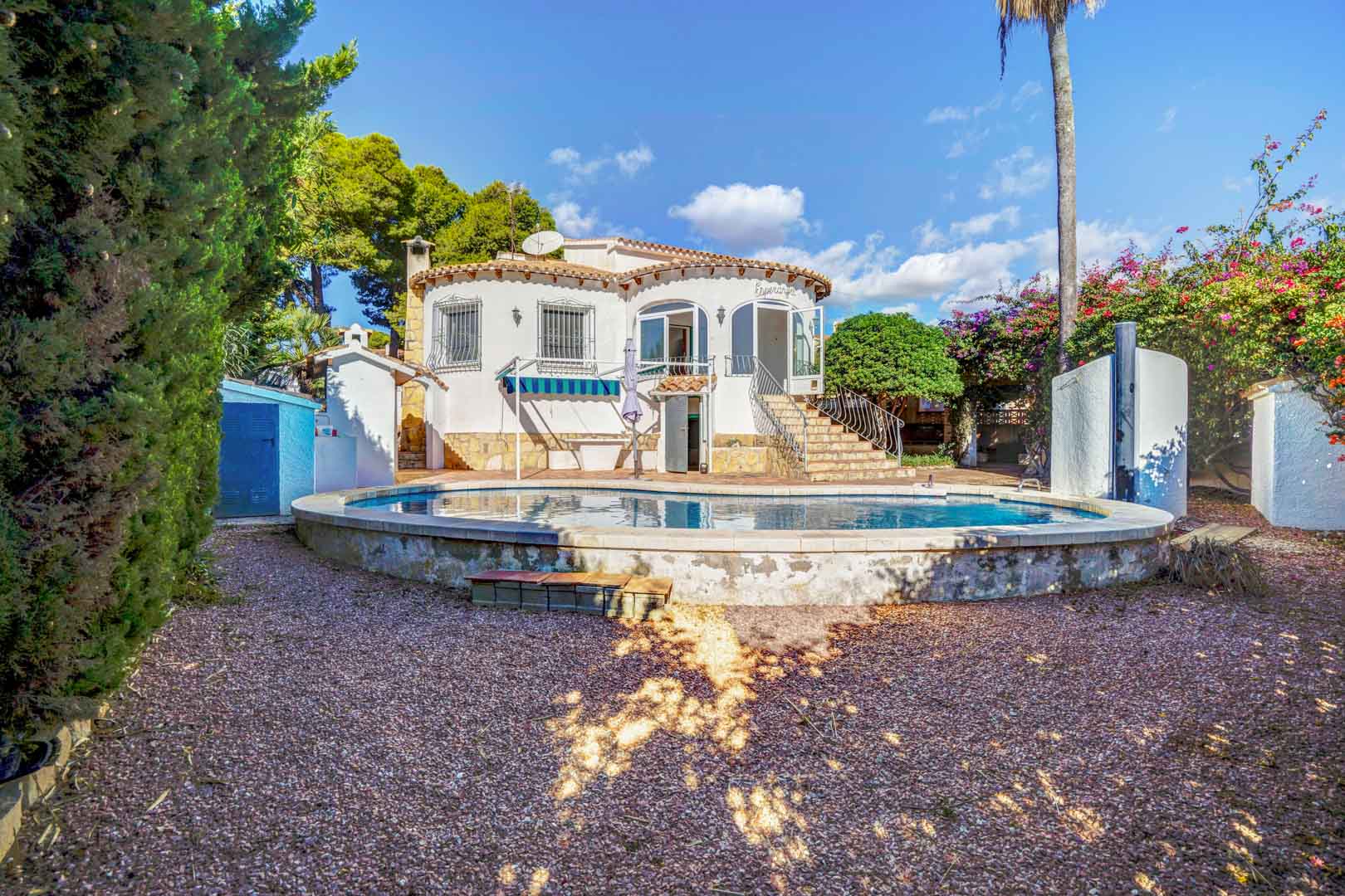 Rückansicht der Villa mit erhöhtem Privatpool, Kiesgarten und Steintreppe, die zur oberen verglasten Terrasse führt.