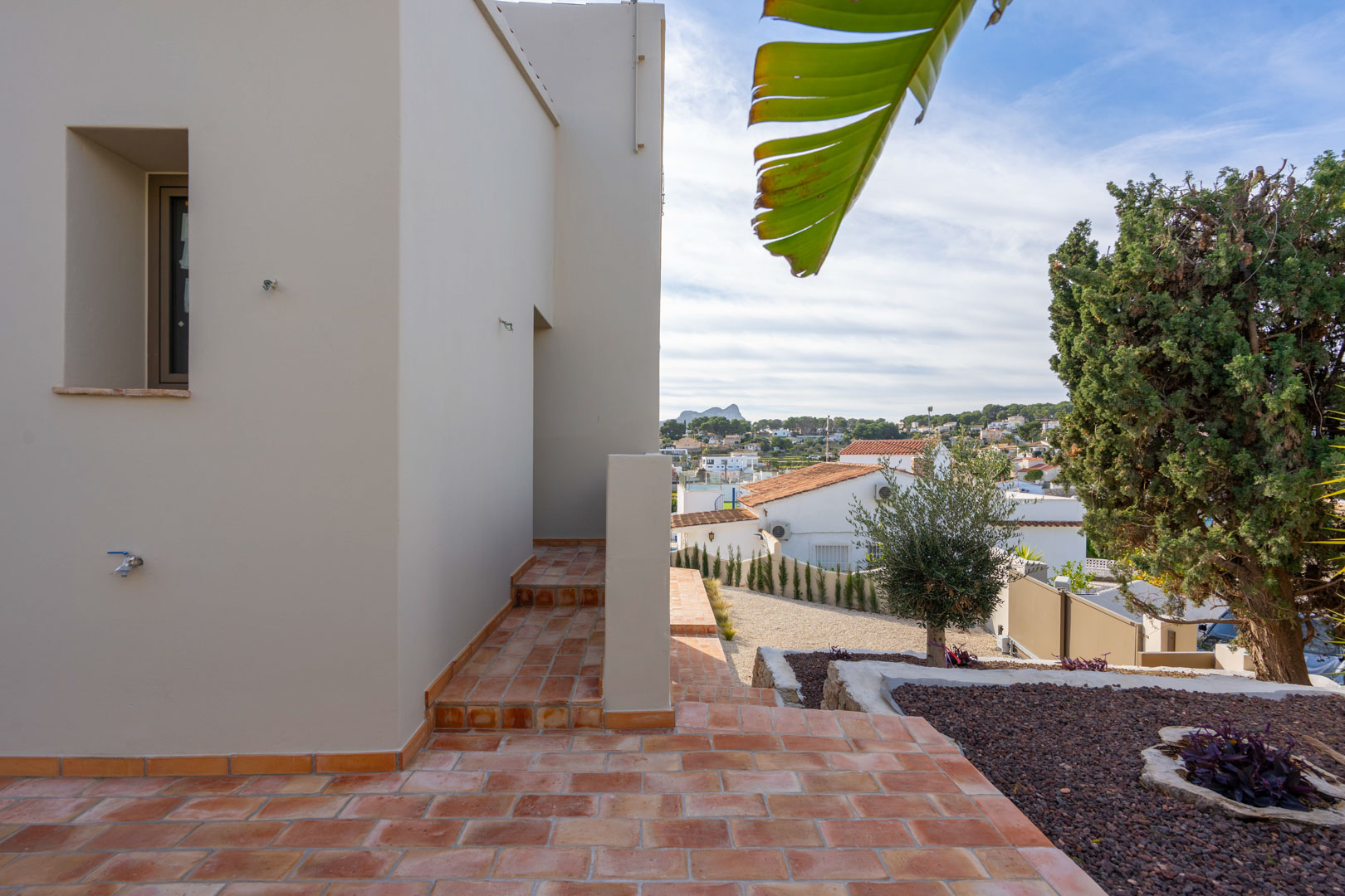 Außenterrasse mit Terrakotta-Fliesen und angelegtem Garten mit Blick auf den Peñón de Ifach und die umliegende Wohngegend von Benissa.