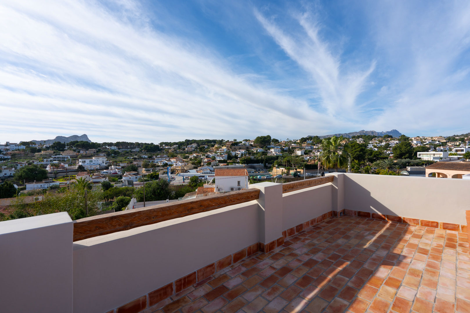 Dachterrasse mit Terrakotta-Fliesen und Holzakzenten, die einen Panoramablick auf den Peñón de Ifach, die Sierra de Bernia und die Umgebung bietet.