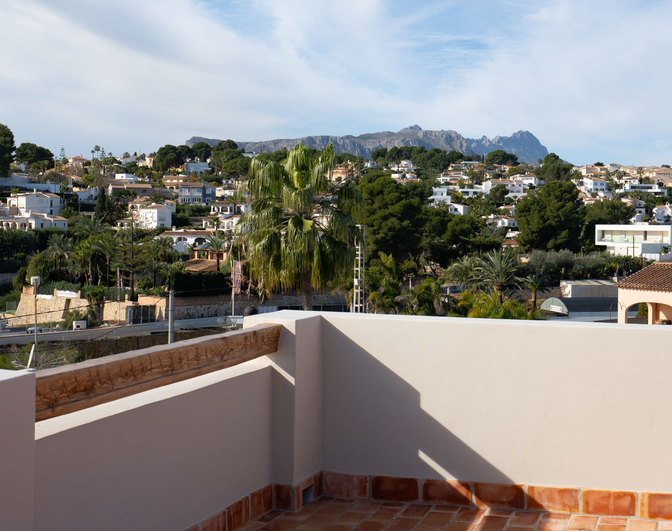 Dachterrasse mit Terrakotta-Fliesen und Panoramablick auf die Sierra de Bernia sowie die umliegende mediterrane Wohngegend.