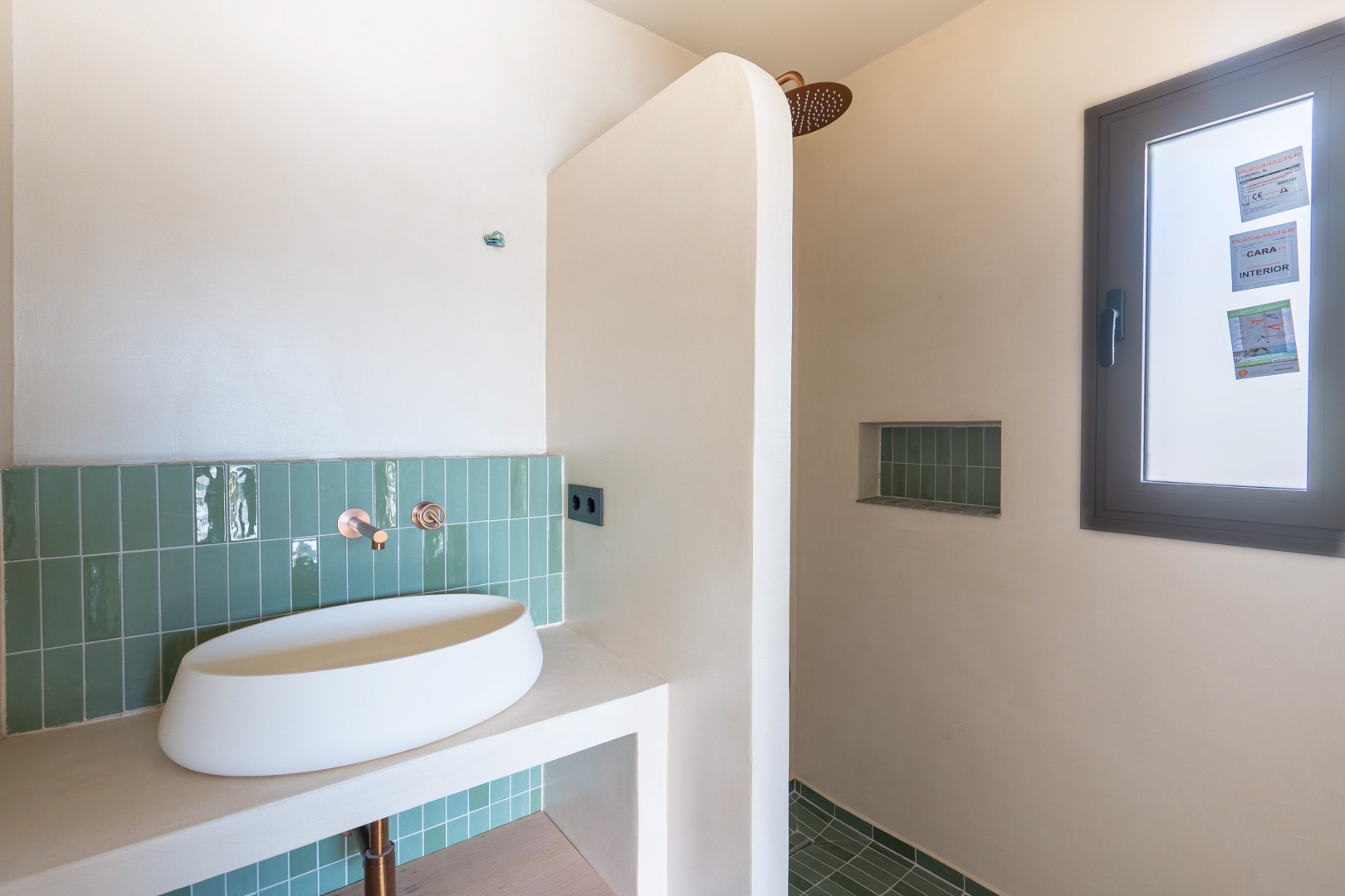 Design-Badezimmer mit Aufsatzwaschbecken, Unterputzarmaturen aus Kupfer und vertikalen grünen Fliesen. Begehbare Dusche mit integrierter Nische und Lehmputz-Oberflächen.