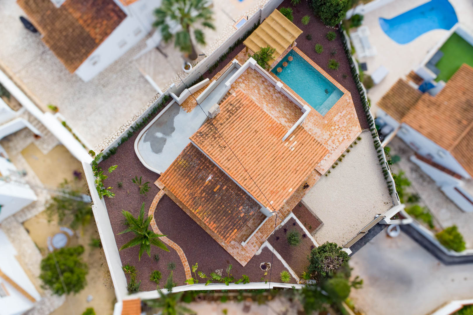 Luftaufnahme der Villa, die die Grundstücksaufteilung, den Pool mit integriertem Sitzbereich, Terrakotta-Terrassen und den mediterran angelegten Garten zeigt.