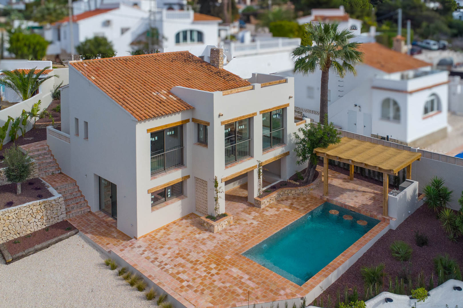 Luftaufnahme der Villa mit neuem Pool, großzügiger Terrakotta-Terrasse und einer Holzpergola mit integriertem Grillbereich im mediterranen Garten.