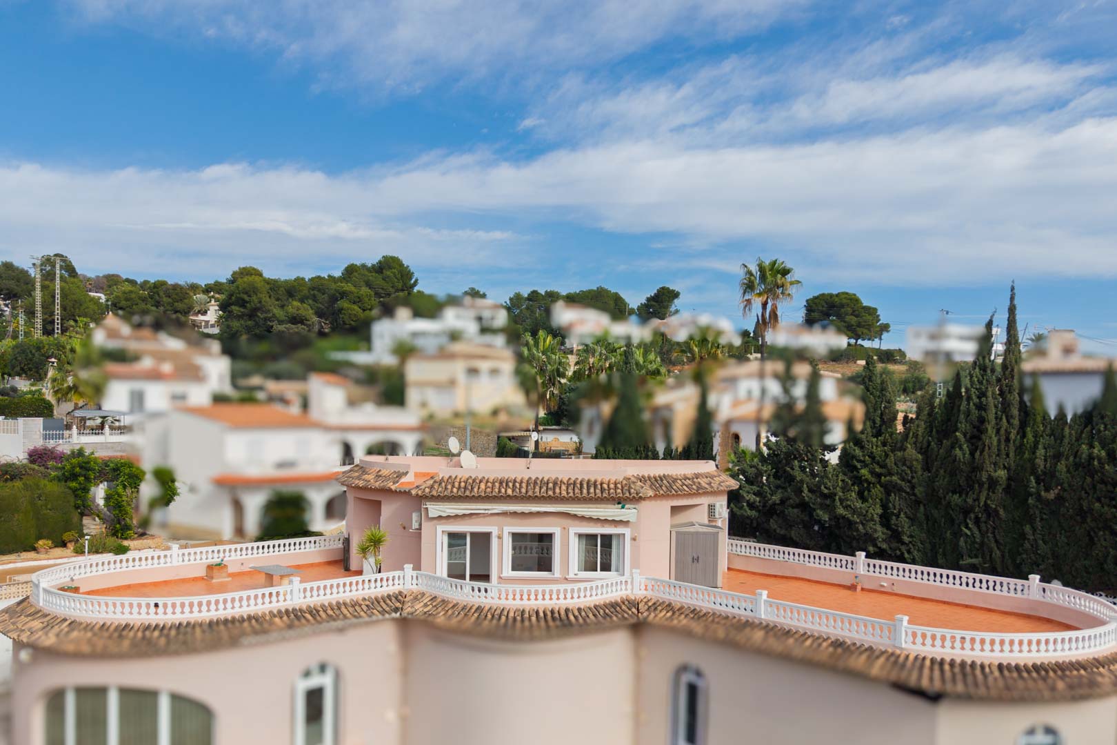 Erhöhte Ansicht des Penthouses mit der weitläufigen, umlaufenden Terrasse, Terrakottaboden und weißen Balustraden in einer grünen Wohngegend.
