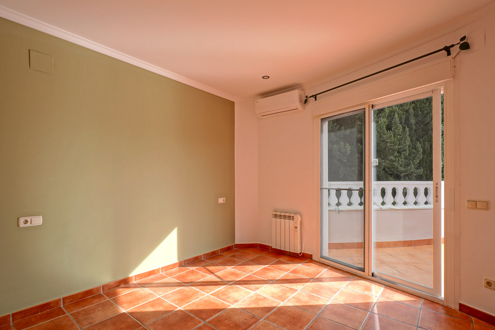 Heller Raum mit grüner Akzentwand, Terrakottafliesen und Terrassenzugang. Ausgestattet mit Split-Klimaanlage, Elektroheizkörper und Deckenleisten.