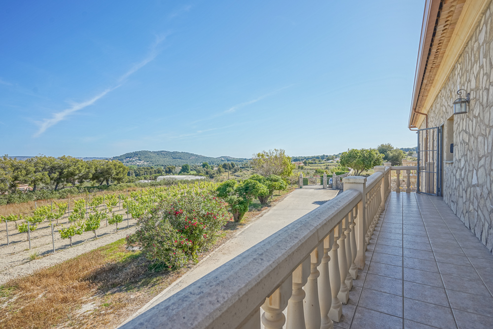 Hochgelegene Terrasse mit klassischer Steinbalustrade und Blick auf die Weinberge und Hügel. Die Fassade besteht aus rustikalem Natursteinmauerwerk.