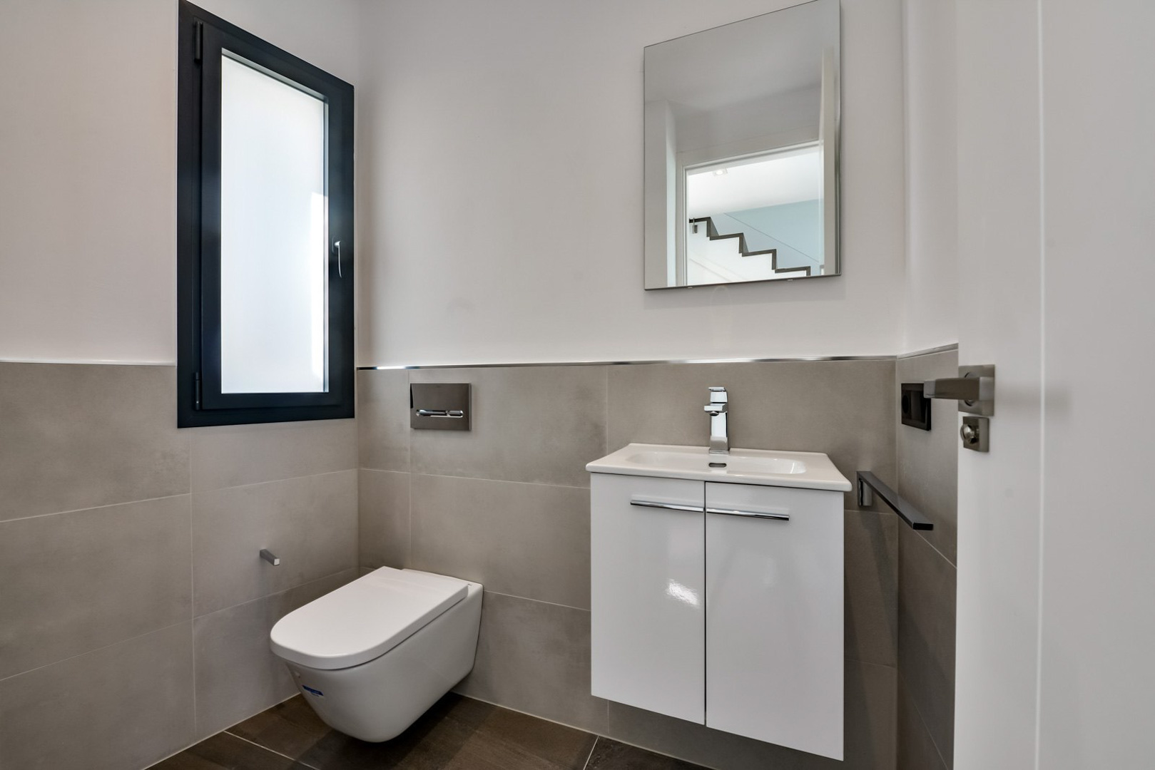 Gäste-WC mit wandhängender Toilette, minimalistischem weißem Waschtisch und mattiertem Glasfenster mit dunklem Rahmen.
