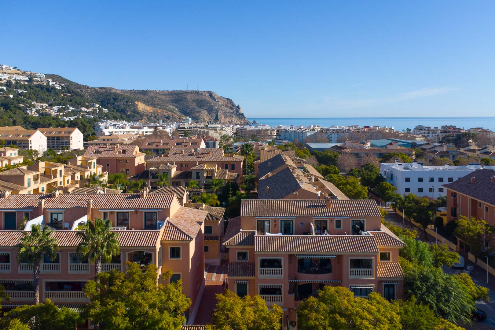 Erhöhte Panorama-Aussicht auf die Floridamar-Anlage mit Terrakottadächern, Blick auf das Mittelmeer und das Cabo de San Antonio im Hintergrund.