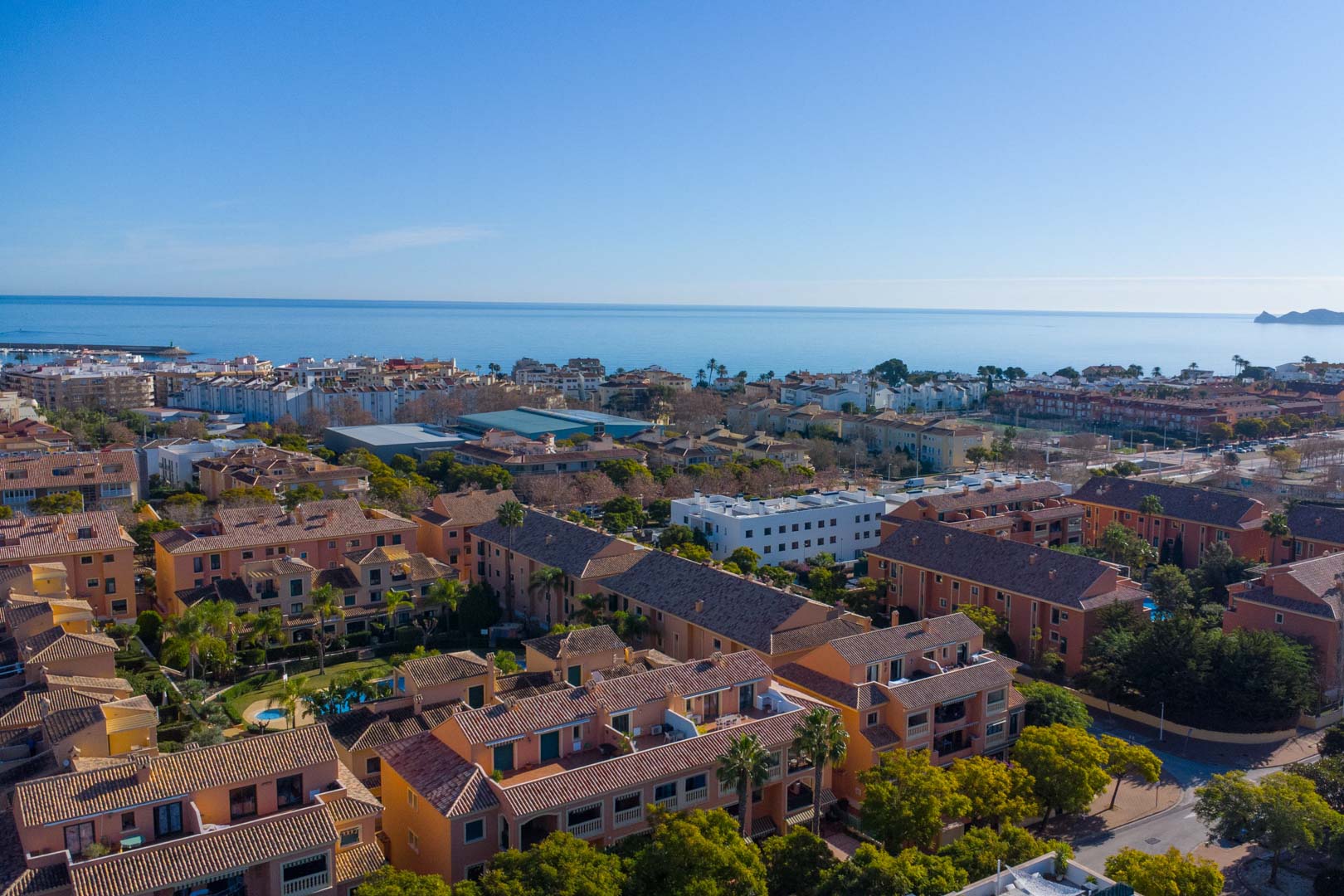 Luftaufnahme der Anlage Floridamar in Jávea mit Blick auf die mediterrane Architektur, gepflegte Gärten und die unmittelbare Nähe zum Meer und Hafen.