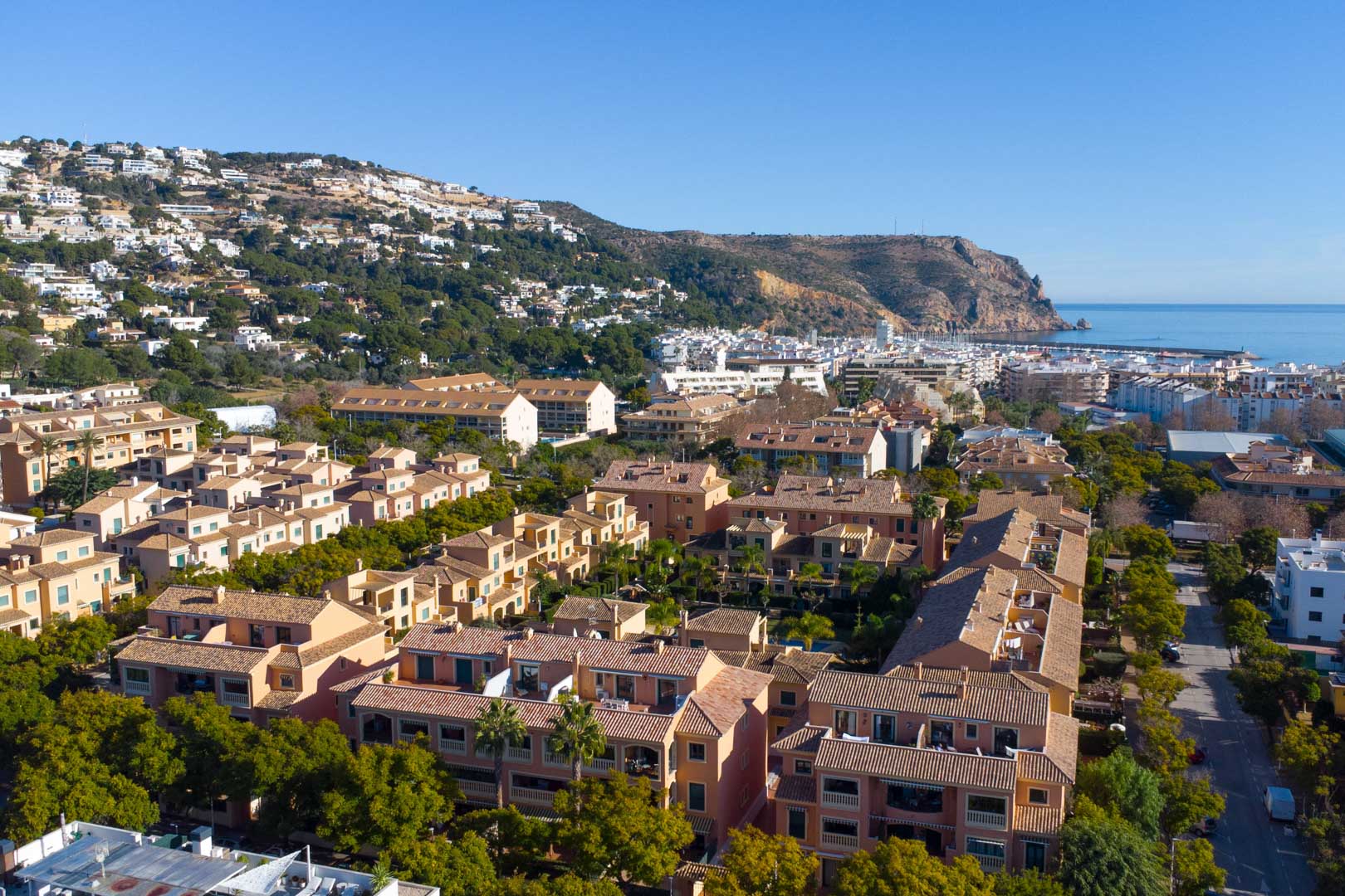 Luftaufnahme der Anlage Floridamar in Jávea mit mediterraner Architektur, gepflegten Grünflächen und Blick auf den Hafen und das Mittelmeer.