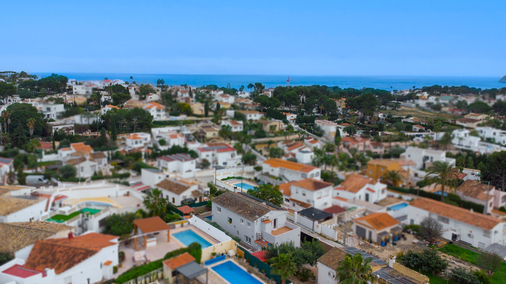 Luftaufnahme der Urbanisation Carrio in Calpe, die die Nähe zum Mittelmeer und die Anordnung der Villen mit privaten Pools zeigt.