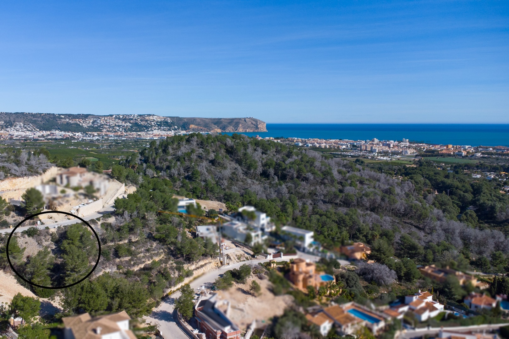 Luftaufnahme des erhöhten Grundstücks in Tosalet 5, umgeben von Pinien, mit Panoramablick auf das Mittelmeer und die Küste von Jávea.